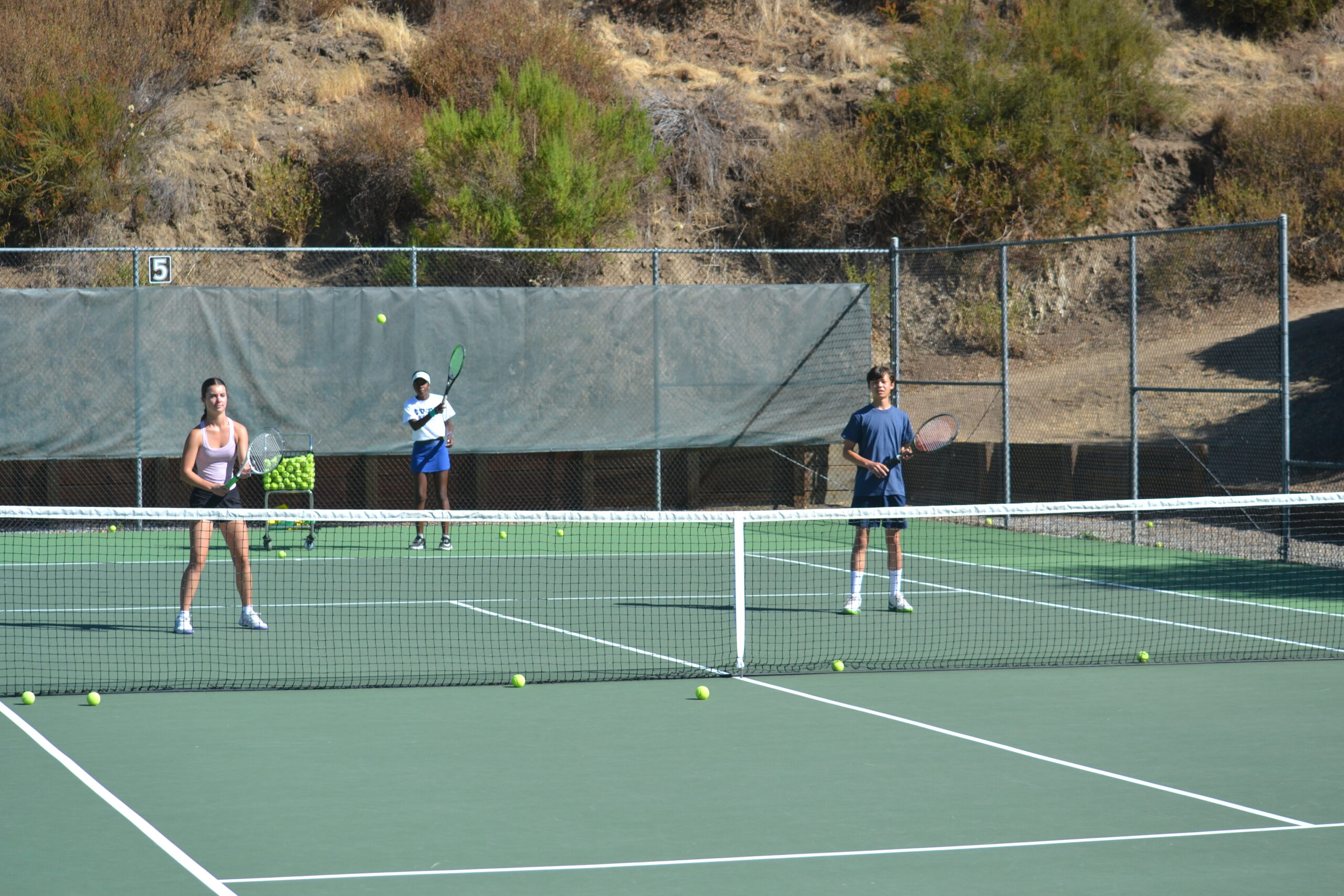 Tennis campers playing during electronics-free summer camp at CVTC